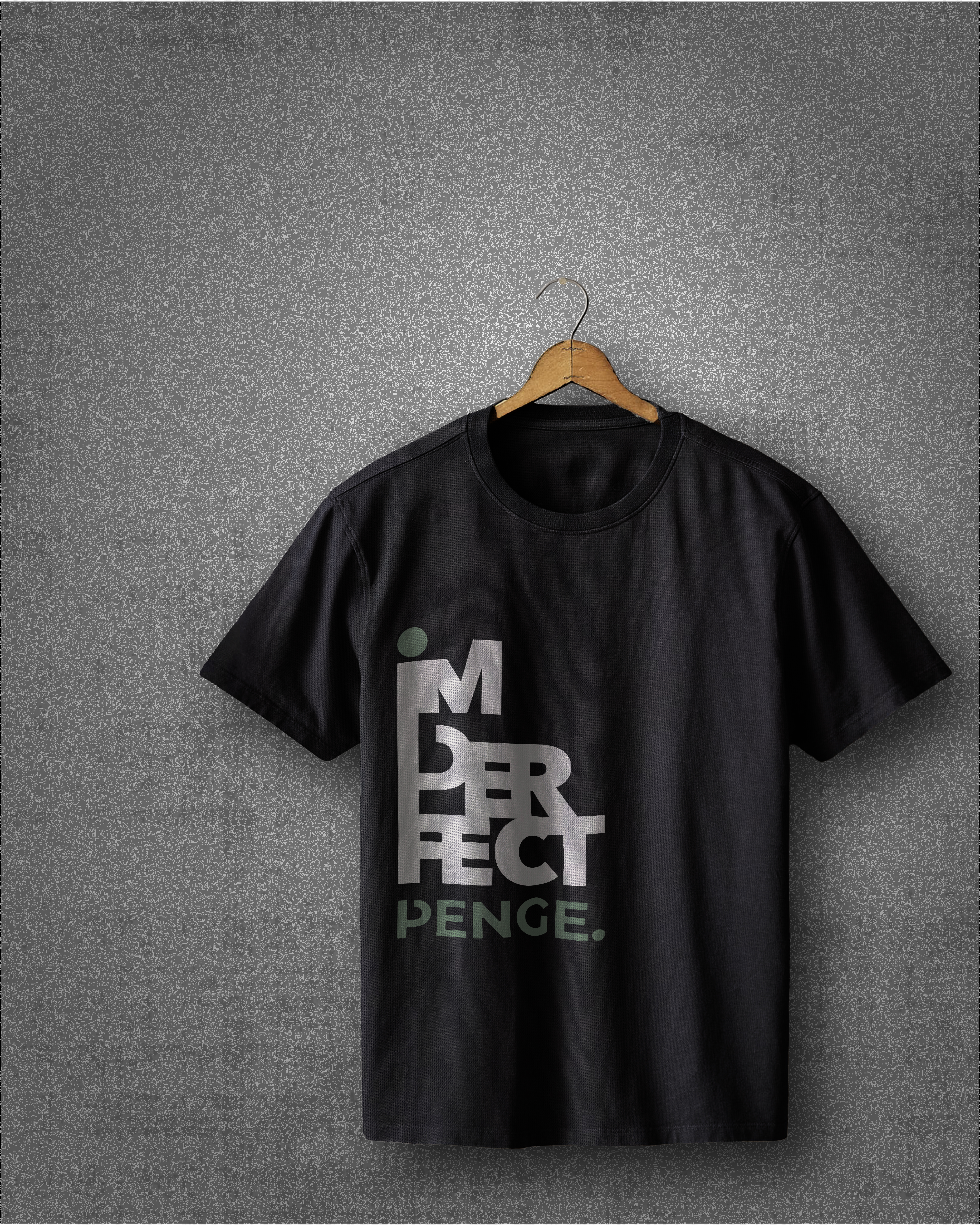 “Black IMPERFECT PENGE tee hanging on a wooden hanger against a textured grey wall, shown in a minimalist, quiet editorial style with bold vertical typography and soft natural shadows.