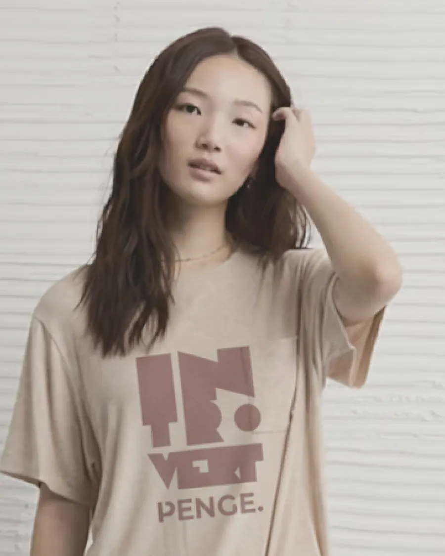 Model in the sand INTROVERT tee against a pale wall